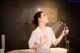 A woman in a white shirt is holding a shower head.