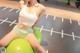 A woman sitting on a green ball in a gym.