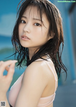 A woman in a pink bra top standing next to a pool.