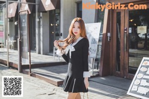 A woman in a black dress is walking down the street.