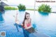 A woman in a pink bikini laying on the edge of a swimming pool.