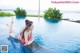 A woman in a pink bikini laying on the edge of a swimming pool.