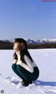 A woman sitting in the snow with her eyes closed.