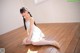 A young woman sitting on the floor in a white dress.