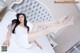 A woman in a white dress laying on a bed.