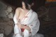 A woman in a white and red kimono sitting on a couch.