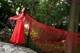 A woman in a red dress standing on a rock.