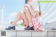 A woman sitting on the steps of a building with her legs crossed.