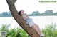 A woman leaning against a tree by the water.