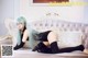 A woman with long blue hair laying on a couch.