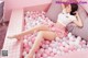 A woman laying in a pink and white ball pit.