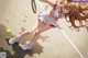 A girl in a white dress playing tennis on a court.