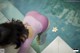 A woman in a pink bathing suit standing next to a pool.