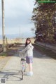 A woman standing next to a bicycle on a road.